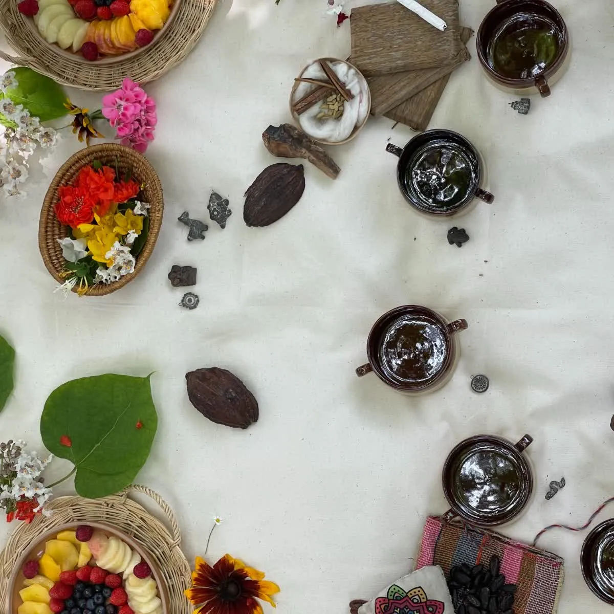 Cacao ceremony altar with flowers, fruit, and cups on Andean textile