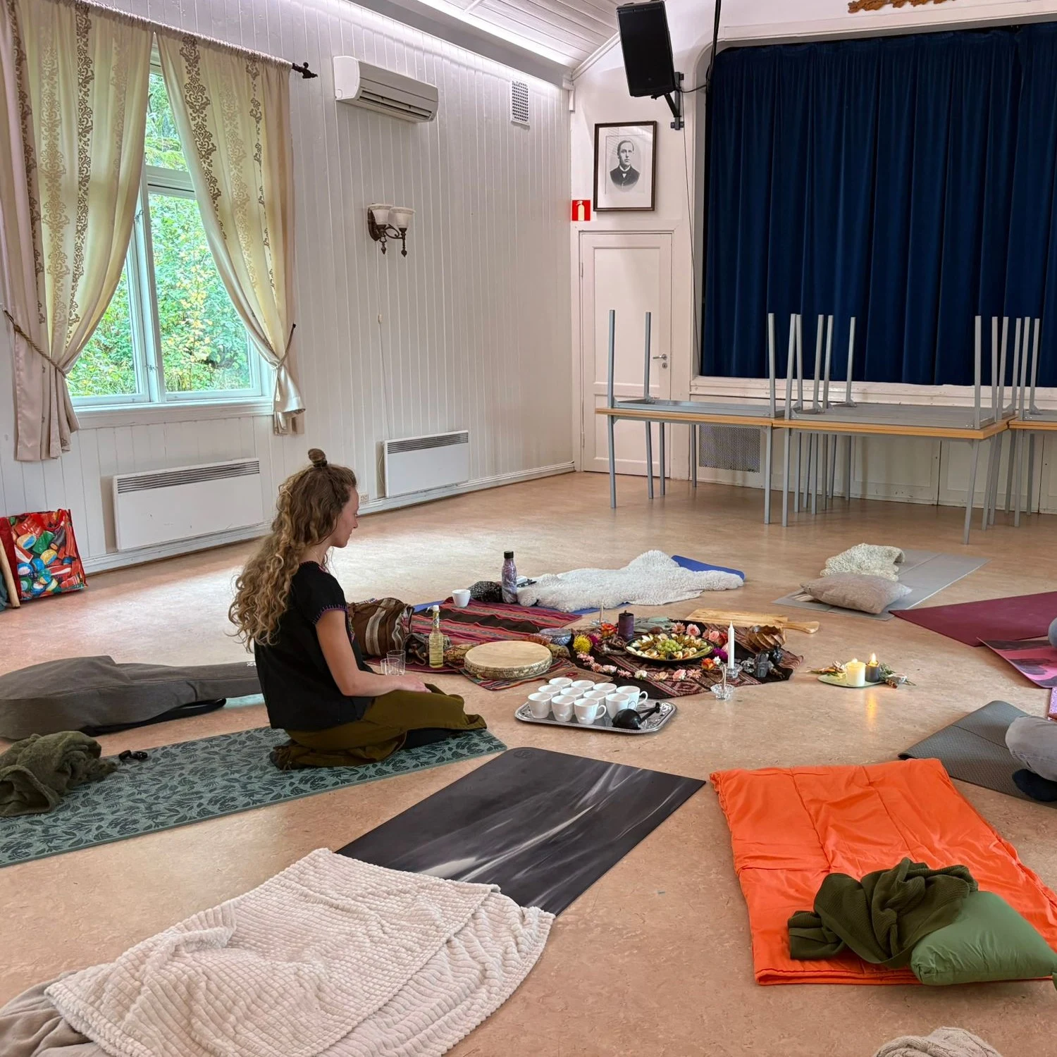 Ceremony circle with mats, cushions, blankets and altar set up in a Norwegian hall